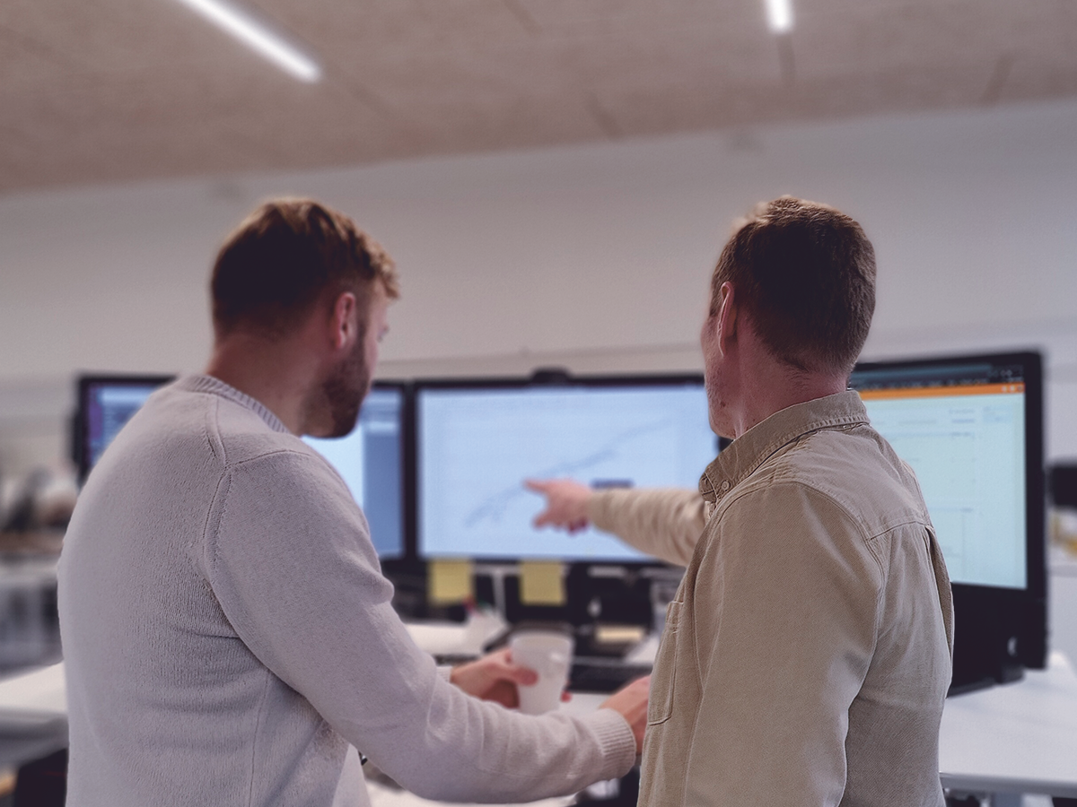 Employees at Exigo show each other 5D financial management for a project on a computer